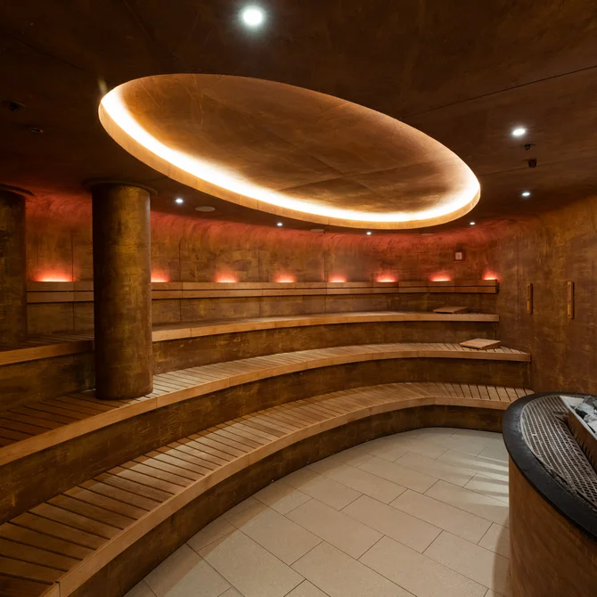 Interior of a modern sauna with curved wooden benches and warm lighting