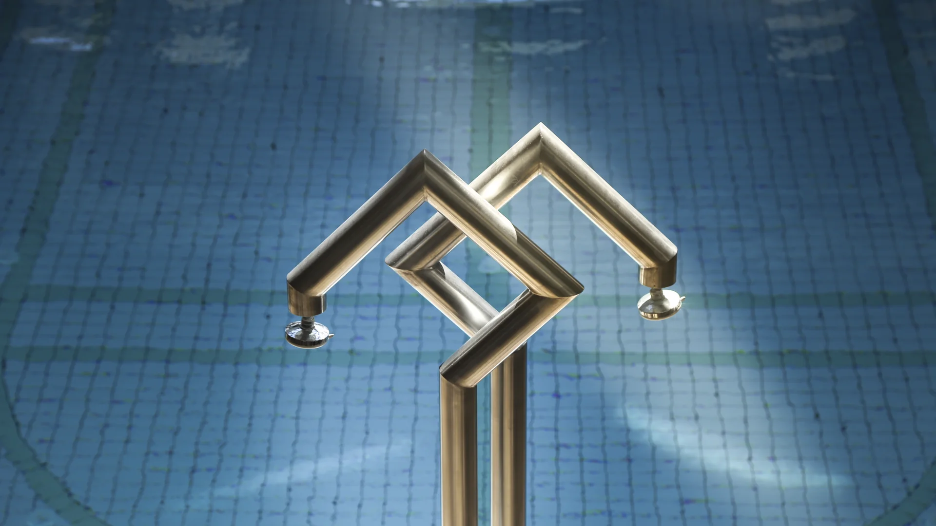 Moderne dreifache Edelstahl-Duschköpfe über Schwimmbecken mit blau gekacheltem Boden