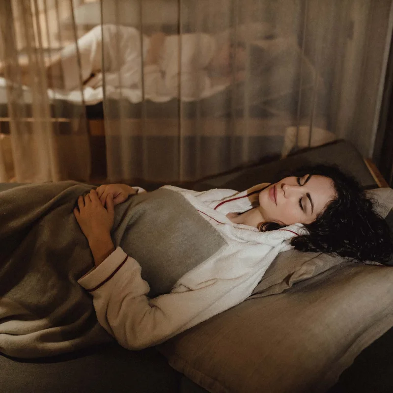 Frau entspannt liegend mit Decke in gemütlichem Raum