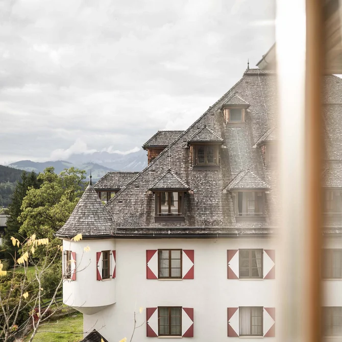 Weißes Haus mit roten Fensterläden und Schindeldach, Blick durch Fenster