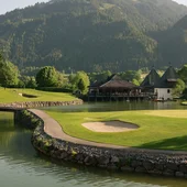 Golfplatz am See mit Bergkulisse und Clubhaus bei sonnigem Wetter