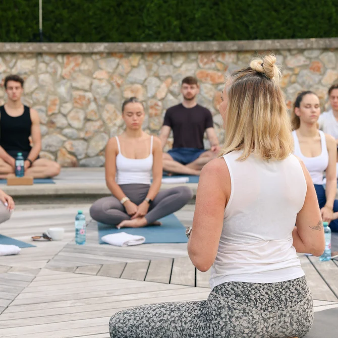 Group of people meditating outdoors on yoga mats